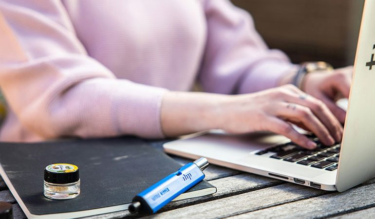 a person using a laptop and a vaping device beside her